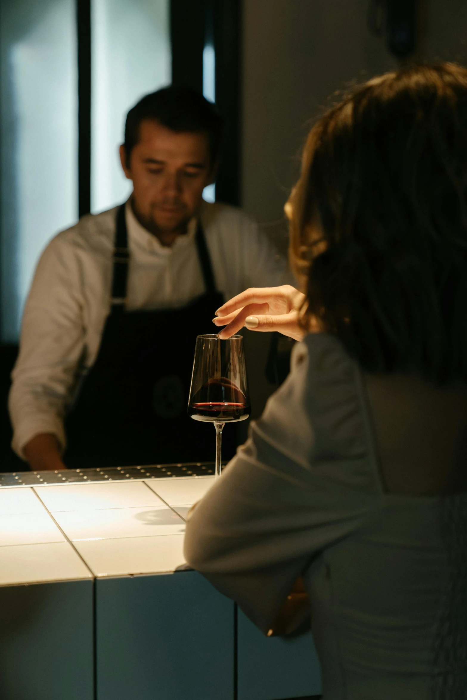 a man and a woman sitting at a bar, inspired by Carlo Randanini, pexels contest winner, renaissance, chef table, under light, holding glass of wine, minimalist