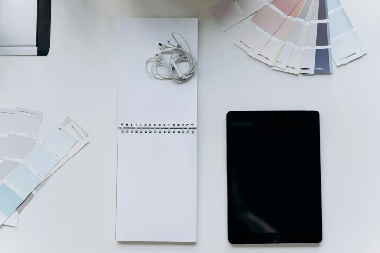 a tablet computer sitting on top of a white desk, trending on unsplash, visual art, 9 9 designs, sheet paper, fine intricate, notebook