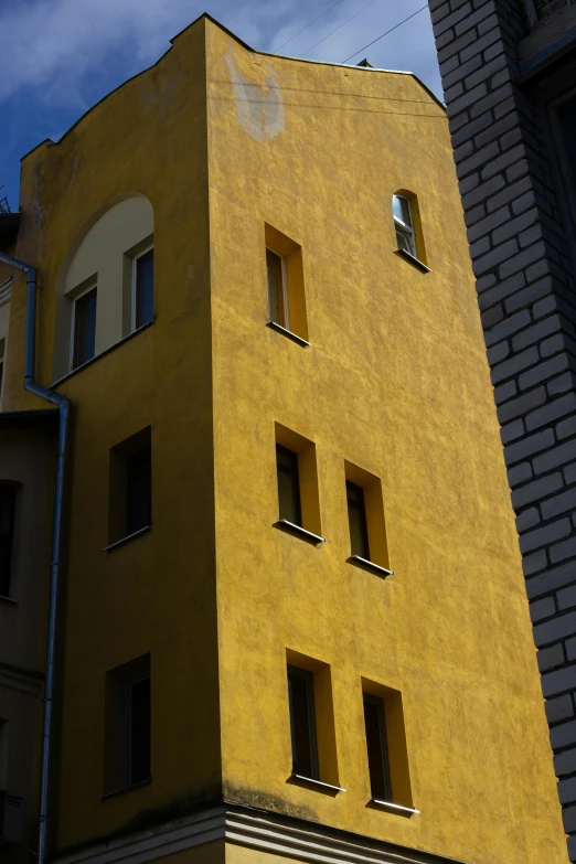 a tall yellow building with lots of windows, inspired by Alexander Rodchenko, old town, prague, stucco walls, mono-yellow