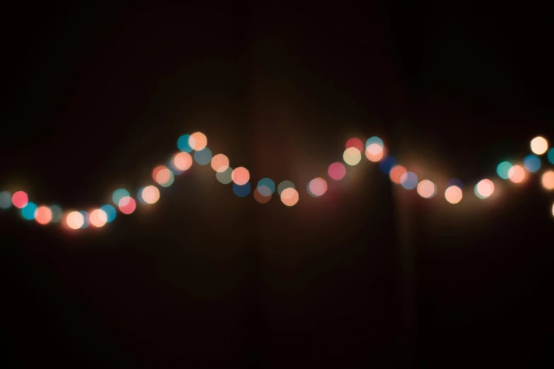 a close up of a string of lights in the dark, inspired by Elsa Bleda, multicoloured, light background, single vague light, laura watson