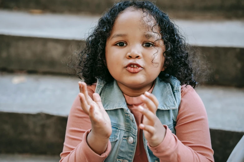 a little girl making a funny face with her hands, pexels contest winner, mixed race woman, thumbnail, high quality picture, 1 2 9 7