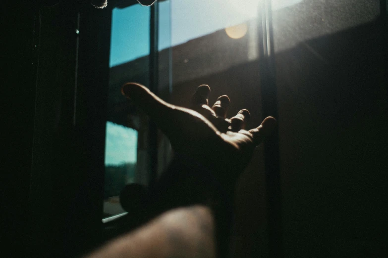 a person's hand reaching out of a window, pexels contest winner, harsh sunlight, instagram post, holding a stuff, standing in a dimly lit room