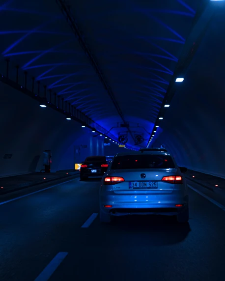 a car driving through a tunnel at night, an album cover, by Julia Pishtar, unsplash contest winner, high blue lights, tourist photo, cars, poorly lit