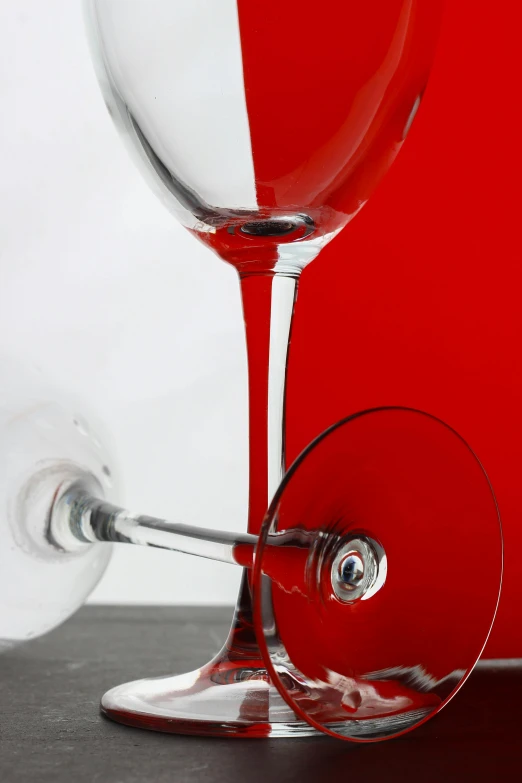 a couple of wine glasses sitting on top of a table, inspired by Arnold Newman, red and white, detail shot, complimentary colours, split in half