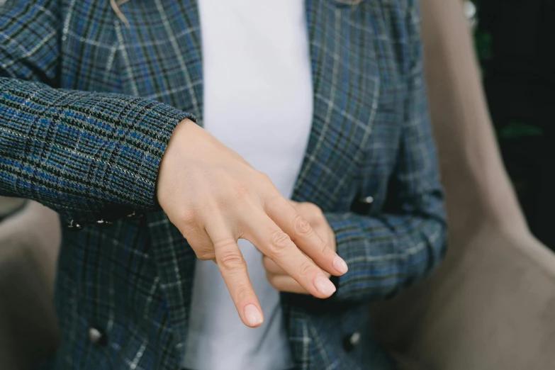 a woman sitting in a chair with a cell phone in her hand, trending on unsplash, hurufiyya, point finger with ring on it, wearing a blue jacket, swollen veins, reaching out to each other