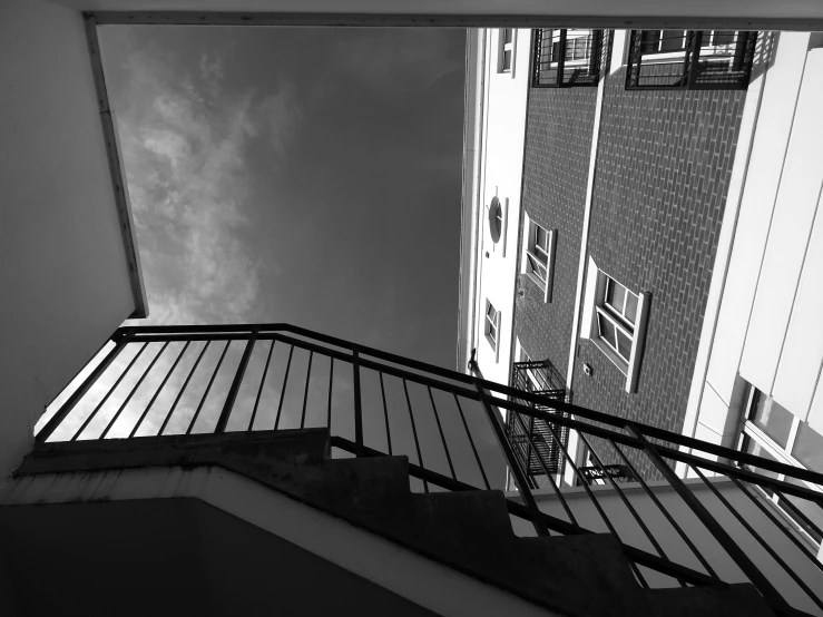 a black and white photo of a staircase, inspired by André Kertész, unsplash, summer sky, eyelevel!!! view!!! photography, balcony, low dutch angle