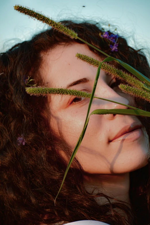 a woman holding a bunch of flowers in front of her face, an album cover, trending on pexels, brown curly hair, woman made of plants, half image, looking away