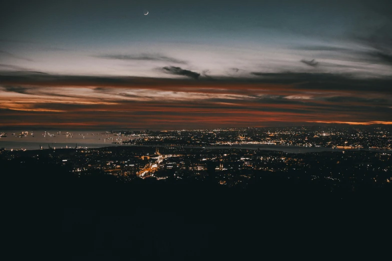 a view of a city at night from the top of a hill, unsplash contest winner, the city of santa barbara, ☁🌪🌙👩🏾, moody sunset, bird's-eye view