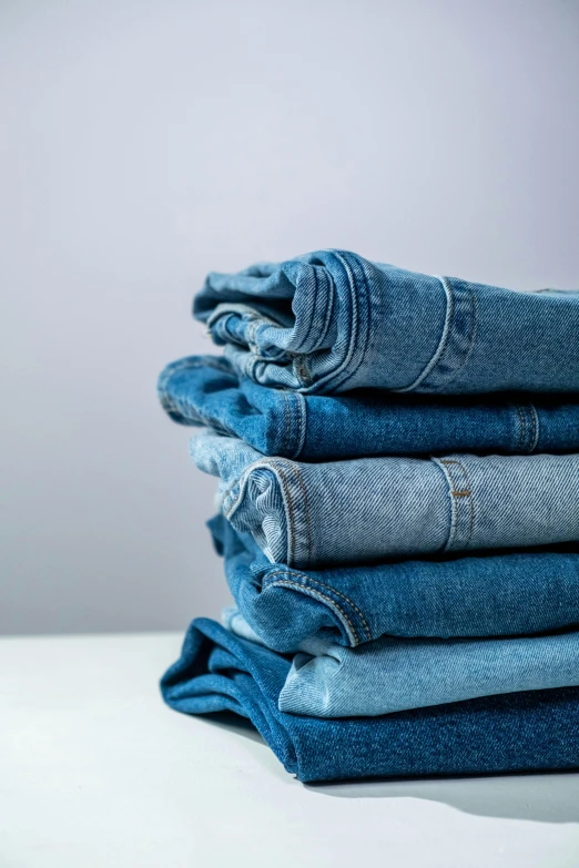a stack of blue jeans on a white table, by Nina Hamnett, trending on unsplash, renaissance, scrubs, 6 colors, thumbnail, large tall