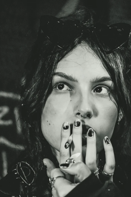 a black and white photo of a woman smoking a cigarette, a black and white photo, inspired by Elsa Bleda, trending on pexels, dirty nails, dafne keen, with pop punk style, scratches on photo