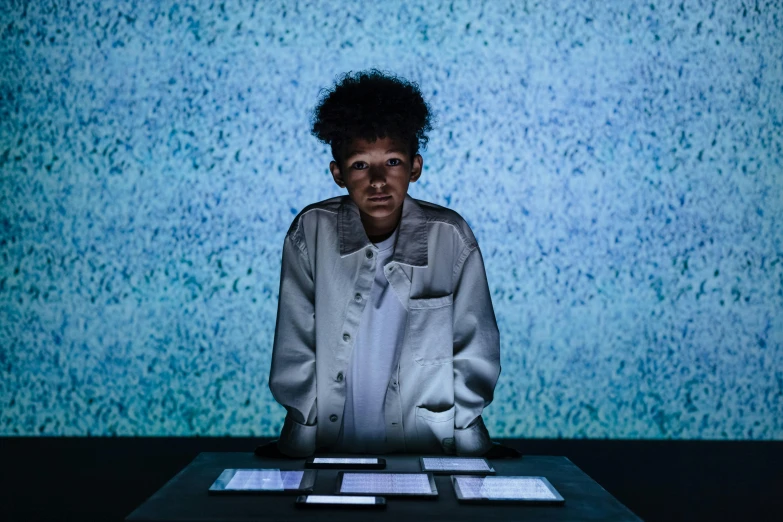 a woman sitting at a table with a laptop in front of her, interactive art, nathalie emmanuel, ryoji, stood in a lab, stone ocean