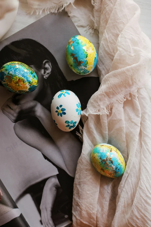 a book sitting on top of a table next to eggs, paint splatter, decorated with flowers, thumbnail, blue