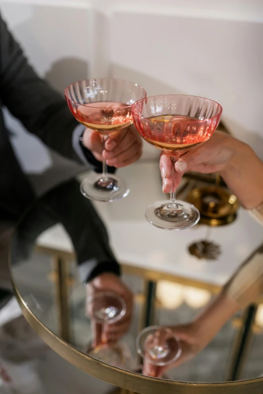 a couple of people that are holding wine glasses, pink and gold, zoomed in shots, lounge, cheers