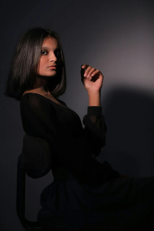 a woman sitting on a chair in a dark room, black bob hair, sleek!!!, taken in the late 2010s, ameera al-taweel