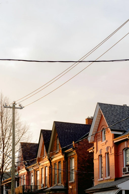 a red stop sign sitting on the side of a road, by Carey Morris, trending on pexels, chimneys on buildings, tangled overhead wires, toronto, at dusk at golden hour