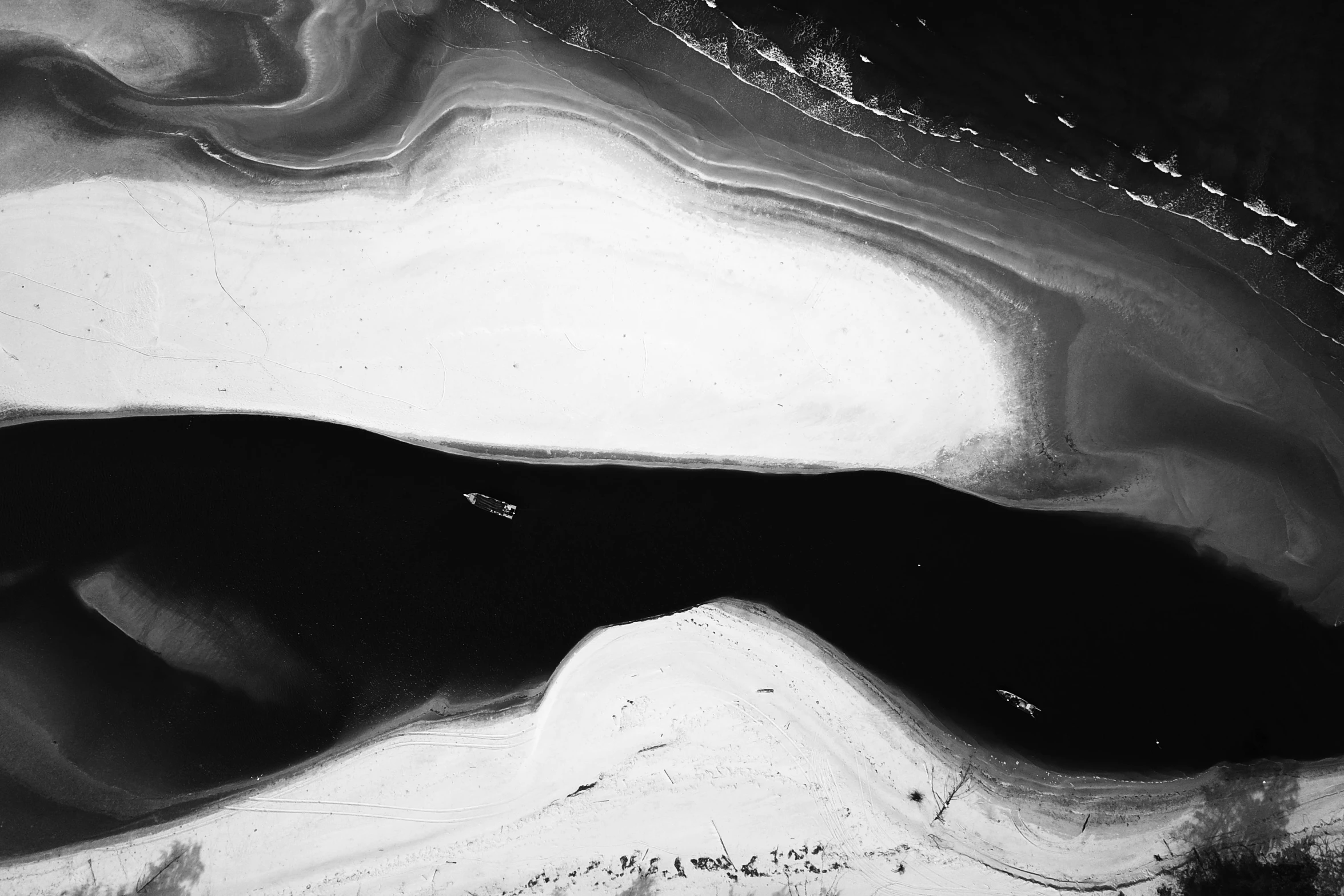 a black and white photo of a body of water, a black and white photo, inspired by René Burri, pexels contest winner, lyrical abstraction, drone photograpghy, white desert, oil spill, “ femme on a galactic shore