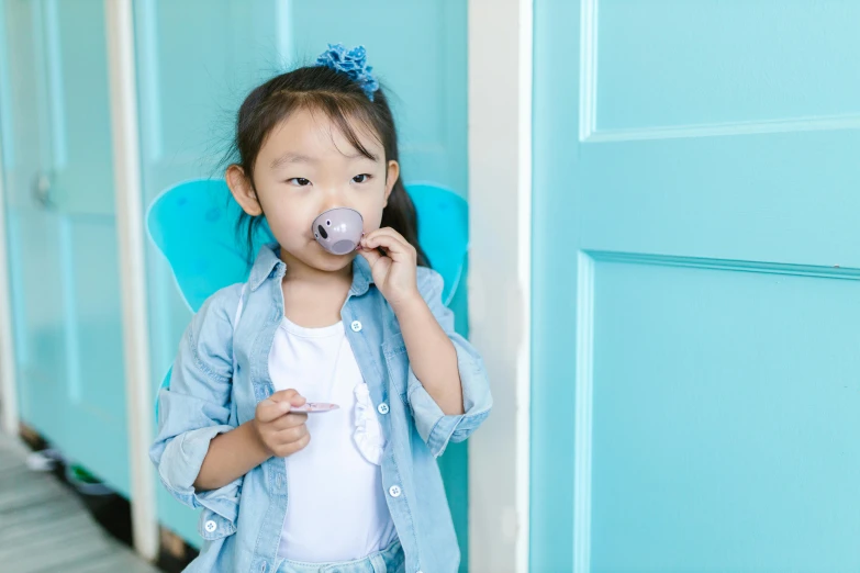 a little girl with a pacifier in her mouth, pexels contest winner, dau-al-set, pale blue outfit, jackie tsai style, with a stethoscope, in style of campbell addy