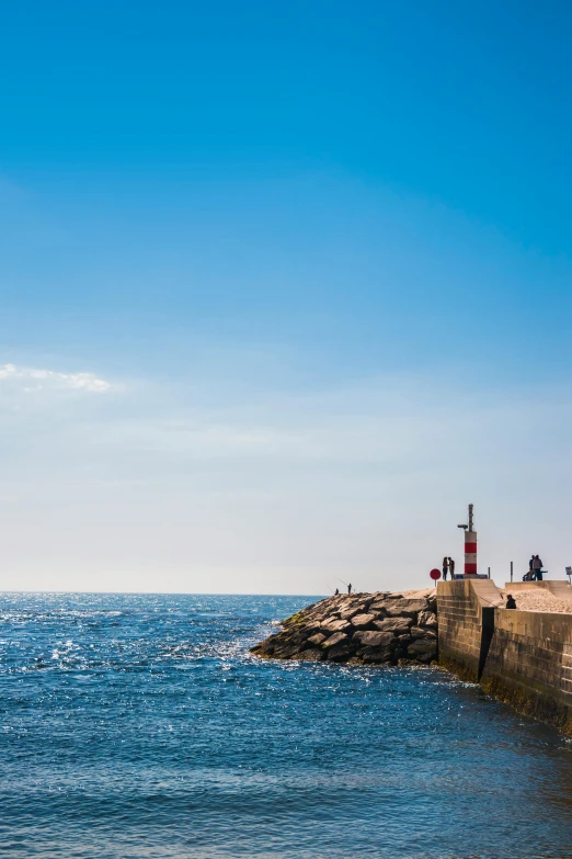 a lighthouse sitting on top of a pier next to the ocean, barcelona, clear blue skies, square, 2022 photograph