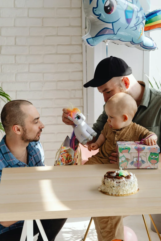 a man holding a baby in front of a birthday cake, a cartoon, pexels contest winner, petros and leonid, on kitchen table, toys, bald