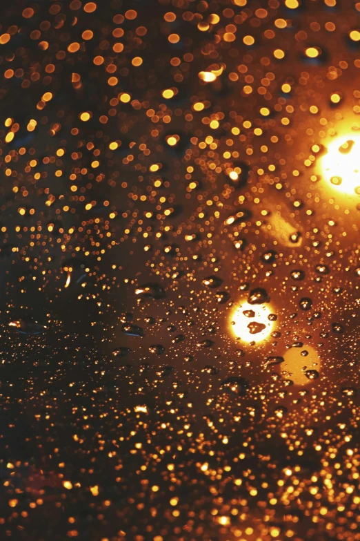 rain drops on a window with a street light in the background, unsplash, light and space, glowing gold embers, sun shines down on the car, fire particles in front, orange lights