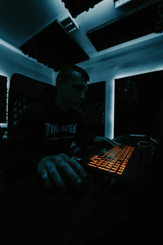 a man sitting in front of a keyboard in a dark room