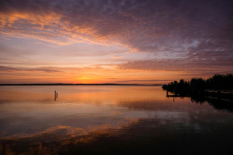 a large body of water with a sunset in the background, by Jan Tengnagel, pexels contest winner, hurufiyya, beautiful tranquil day, lakeside, greg rutwoski, award winning masterpiece photo