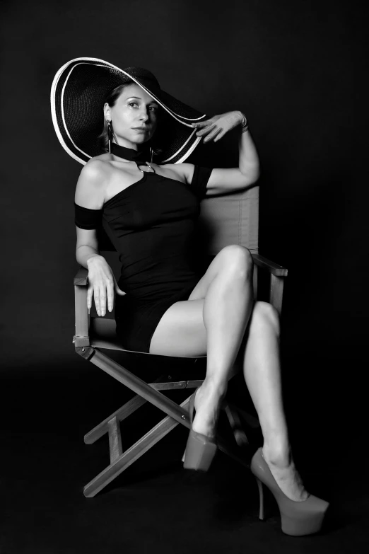 a black and white photo of a woman sitting in a chair, inspired by Helmut Newton, wearing black dress and hat, evangeline lilly, various posed, loreta lux