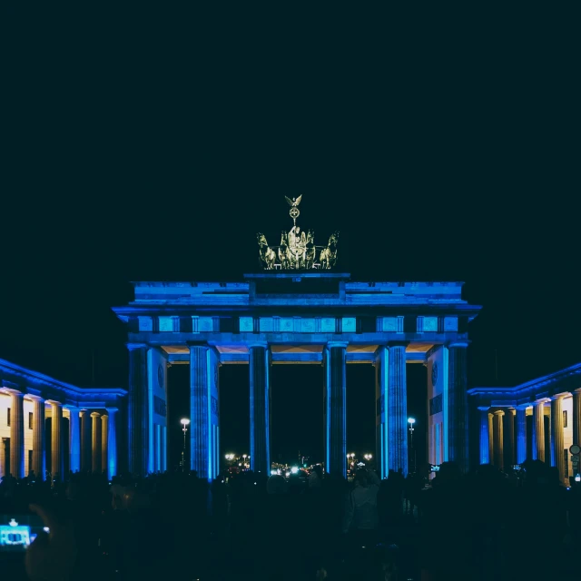 a group of people that are standing in front of a building, pexels contest winner, berlin secession, blue headlights, arch, german chancellor, festival. scenic view at night