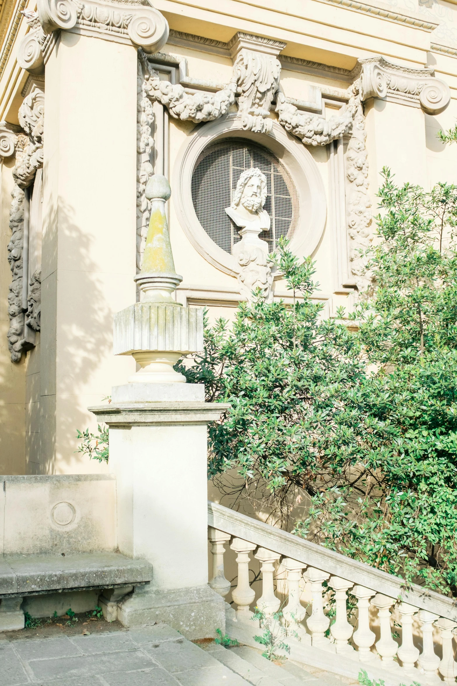 a man sitting on a bench in front of a building, a statue, inspired by Mihály Munkácsy, rococo, dense with greenery, walking down a marble stairwell, florentine school, slightly sunny