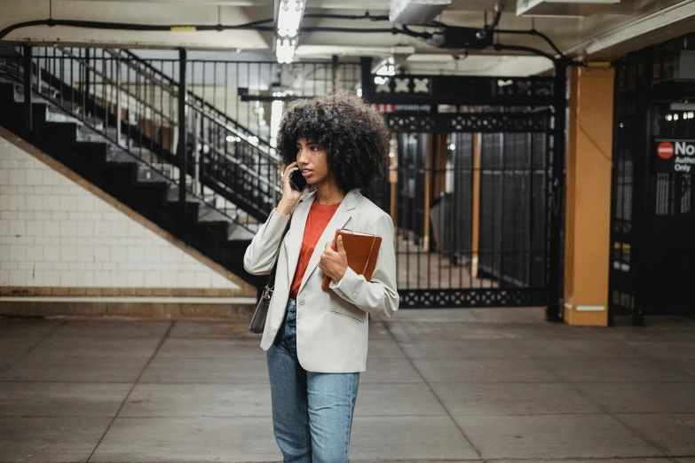 a woman talking on a cell phone in a subway station, trending on pexels, wearing a blazer, holding notebook, ashteroth, girl standing