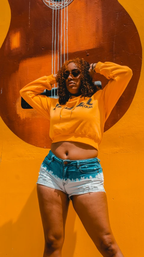 a woman posing in front of a guitar, trending on pexels, graffiti, booty shorts, colors: yellow, 15081959 21121991 01012000 4k, jamaican colors