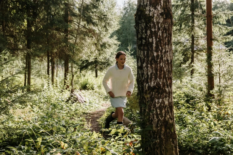 a man walking through a lush green forest, a portrait, by Jaakko Mattila, unsplash, hurufiyya, wearing a white sweater, nina tryggvadottir, full body image, delightful surroundings