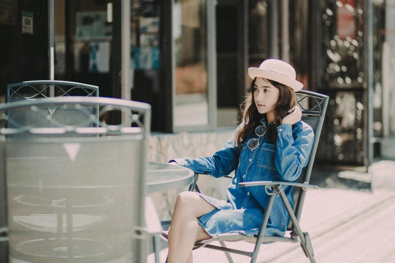 a woman sitting in a chair talking on a cell phone, pexels contest winner, double denim, korean girl, wearing a cute hat, full body:: sunny weather::