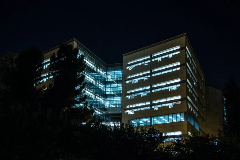 a couple of tall buildings lit up at night, inspired by Francisco Zúñiga, brutalism, medical research facility, 1600 south azusa avenue, exterior photo, uhq