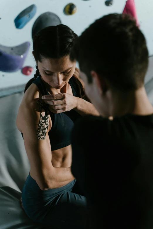 a woman sitting on top of a bed next to a man, a tattoo, pexels contest winner, in a gym, fist training, profile image, embracing