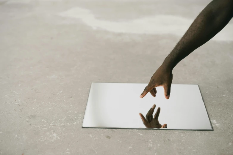 a close up of a person touching a mirror, by Nina Hamnett, white concrete floor, tabletop, unframed, rectangle