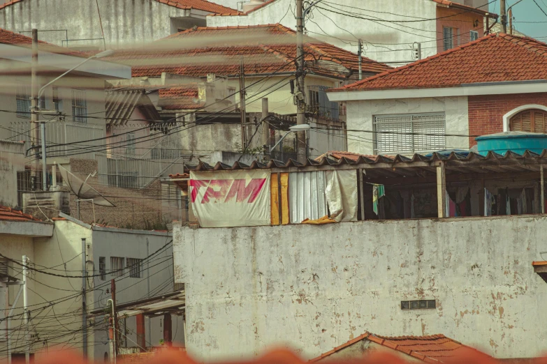 a bunch of buildings that are next to each other, a colorized photo, by Elsa Bleda, pexels contest winner, photorealism, hiding in the rooftops, brazilian, makeshift house, faded red colors