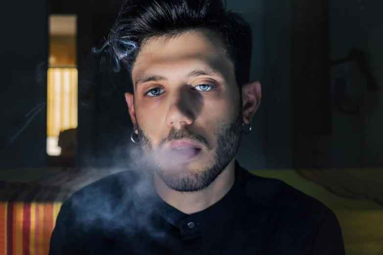 a man smoking a cigarette in a dark room, an album cover, inspired by Elsa Bleda, pexels contest winner, hyperrealism, with anxious piercing eyes, gal yosef, ganja, headshot profile picture