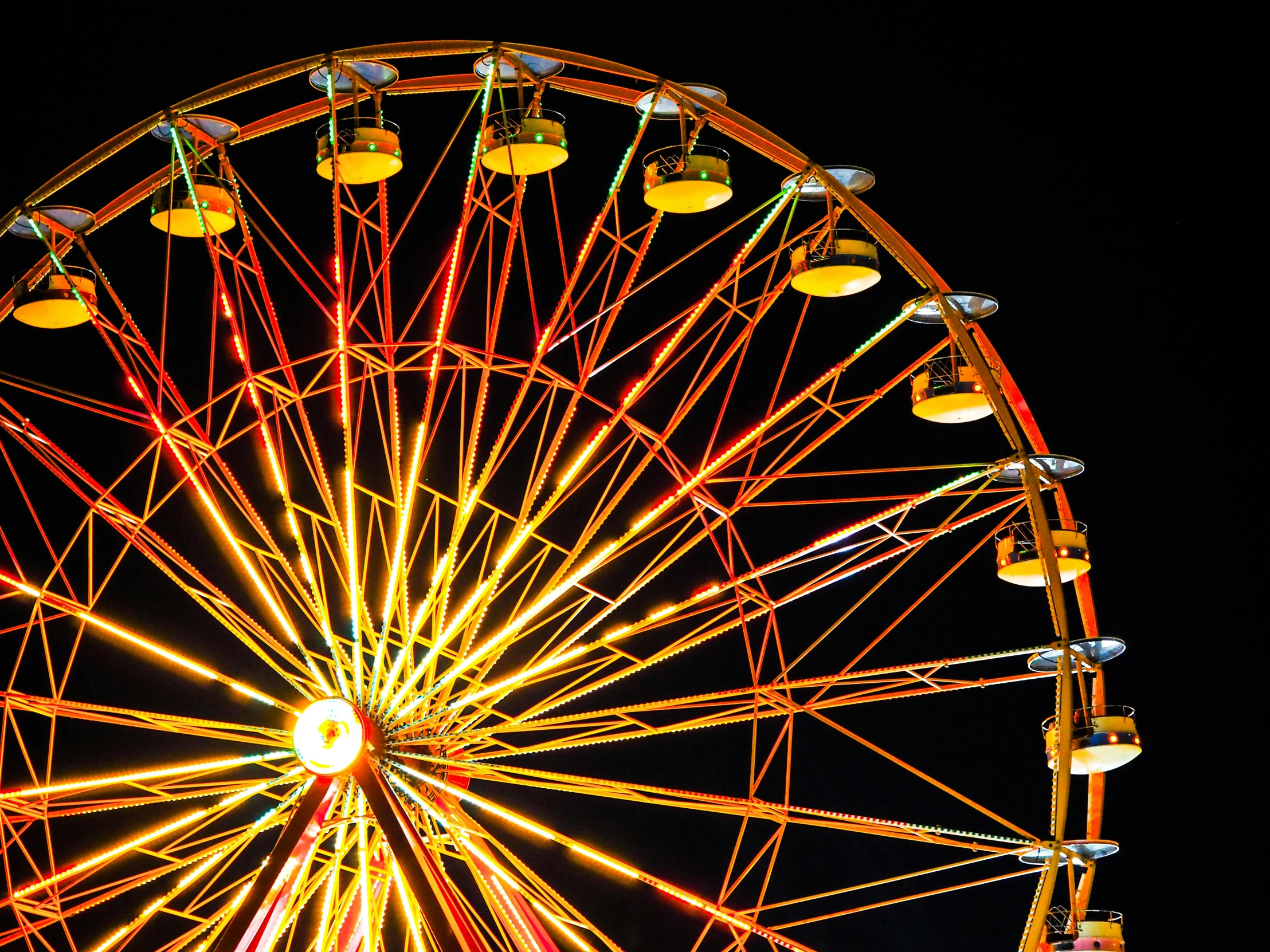 a ferris wheel is lit up at night, pexels contest winner, yellow and orange color scheme, outdoor fairgrounds, on black background, profile image