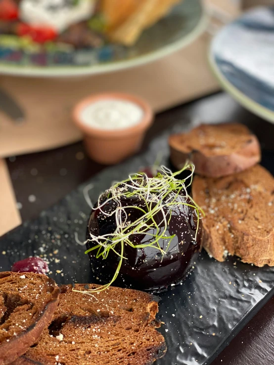 a close up of a plate of food on a table, dark purple scheme, brown bread with sliced salo, moss ball, promo image