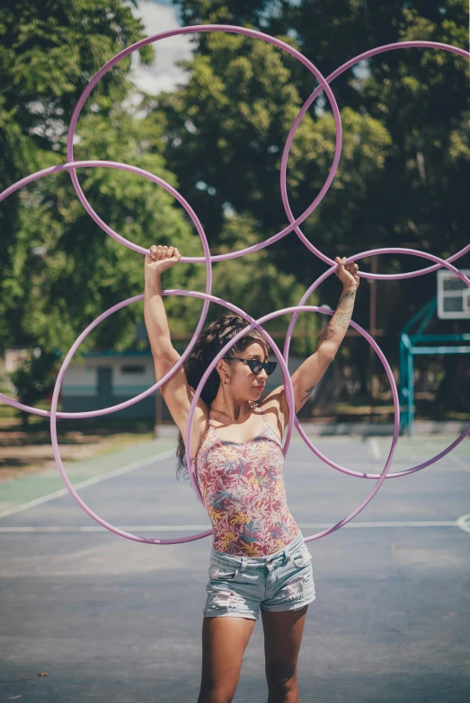 a woman standing on top of a basketball court holding a hoop, pexels contest winner, kinetic art, purple tubes, at a park, circles, bubblegum