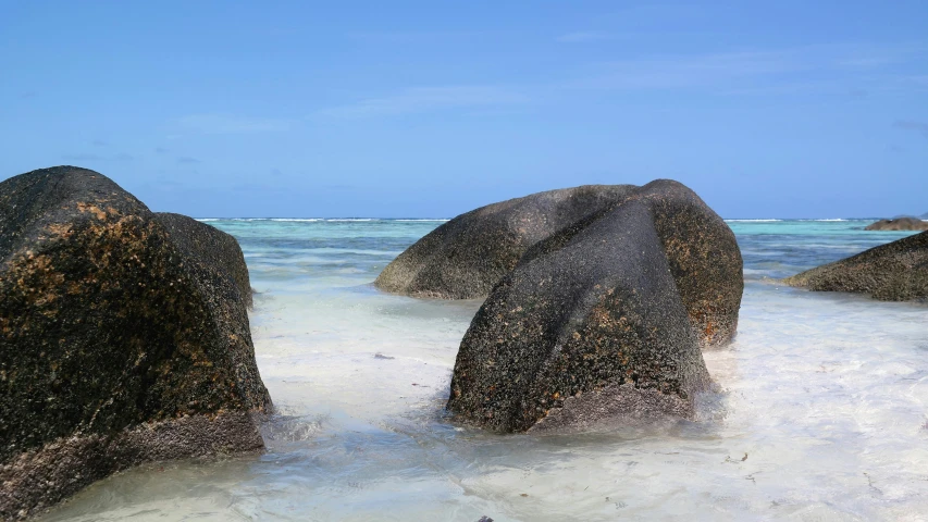 a couple of large rocks sitting on top of a sandy beach, clear water, sarenrae, many islands, highly upvoted