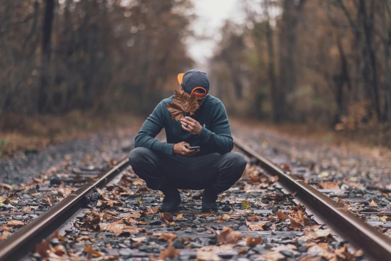 a man kneeling on a train track holding a cat, pexels contest winner, covered in fallen leaves, with depressive feeling, profile picture 1024px, profile pic