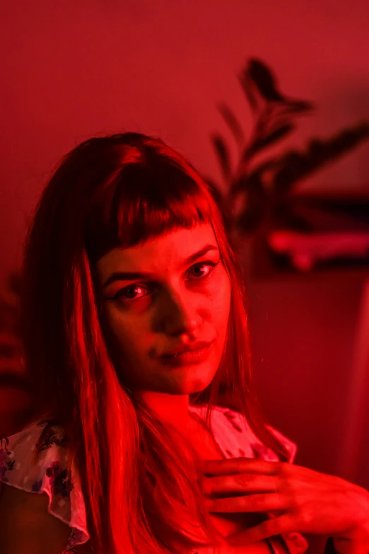 a woman sitting in front of a red light, pexels contest winner, serial art, full bangs, portrait sophie mudd, in front of a computer, cinematic headshot portrait