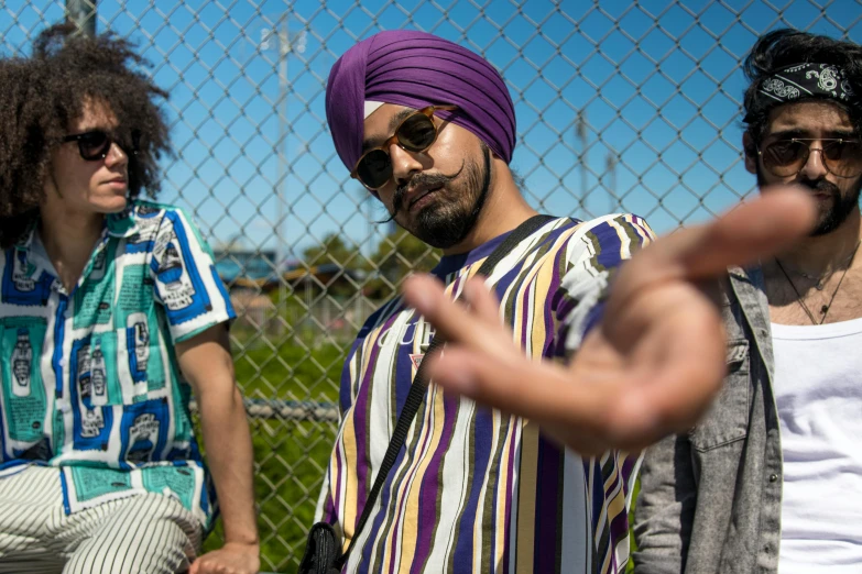 a group of young men standing next to each other, a portrait, inspired by Manjit Bawa, pexels, graffiti, wearing a turban, purple, chappie in an adidas track suit, in the sun