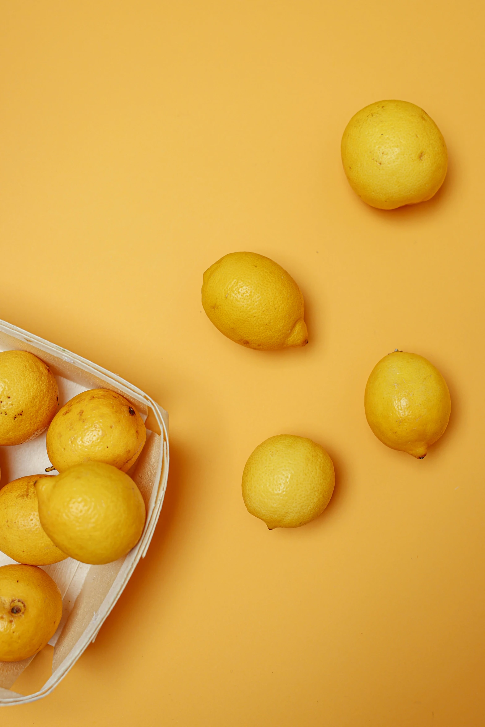 a plastic container filled with lemons on top of a yellow surface, thumbnail, lumi, market, trimmed