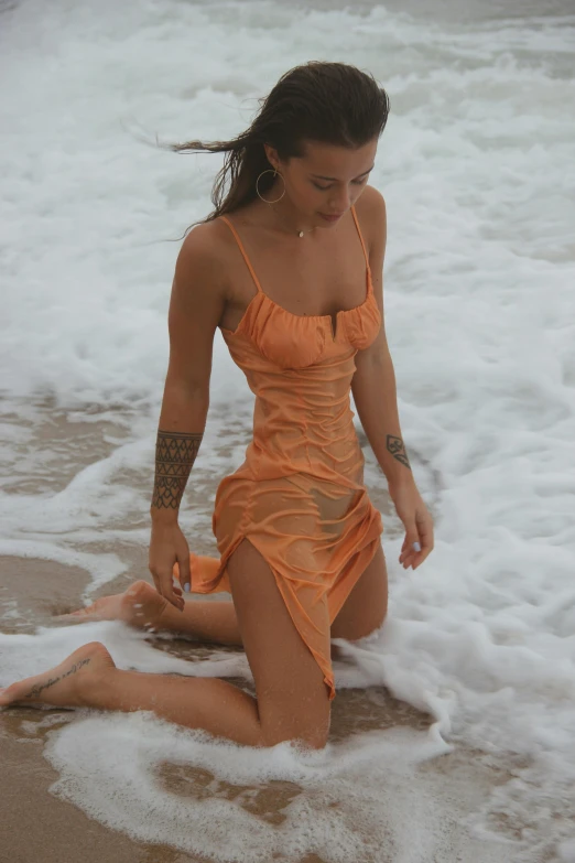 a woman in an orange dress sitting on the beach, by Robbie Trevino, drenched body, slightly tanned, soft silk dress, gif