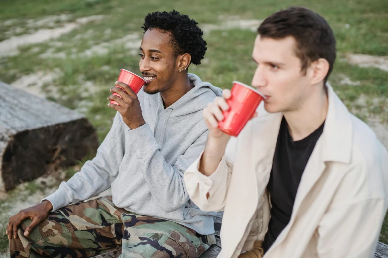 a couple of men sitting next to each other on a bench, trending on pexels, awkwardly holding red solo cup, avatar image, people on a picnic, thin young male