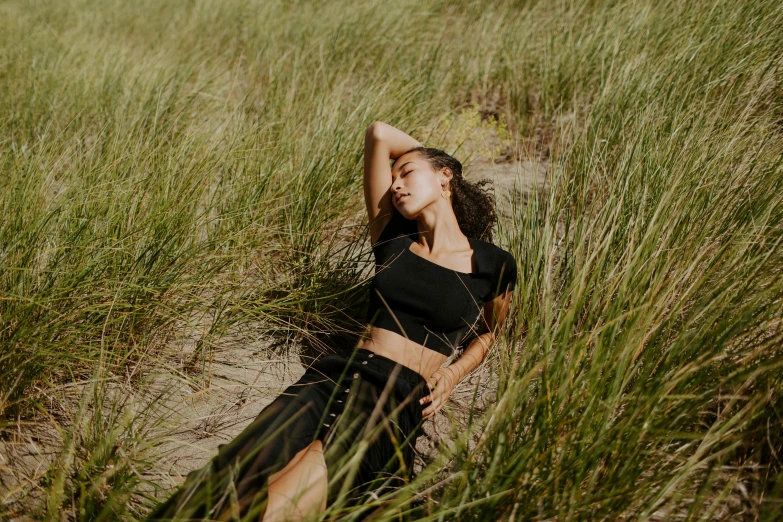 a woman laying in a field of tall grass, unsplash, renaissance, posing on a beach with the ocean, casual black clothing, avatar image, wearing a cropped tops