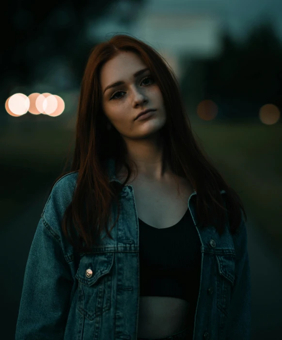 a woman standing in the middle of a road at night, an album cover, inspired by Elsa Bleda, pexels contest winner, realism, portrait of a red haired girl, wearing a jeans jackets, wearing a cropped black tank top, headshot